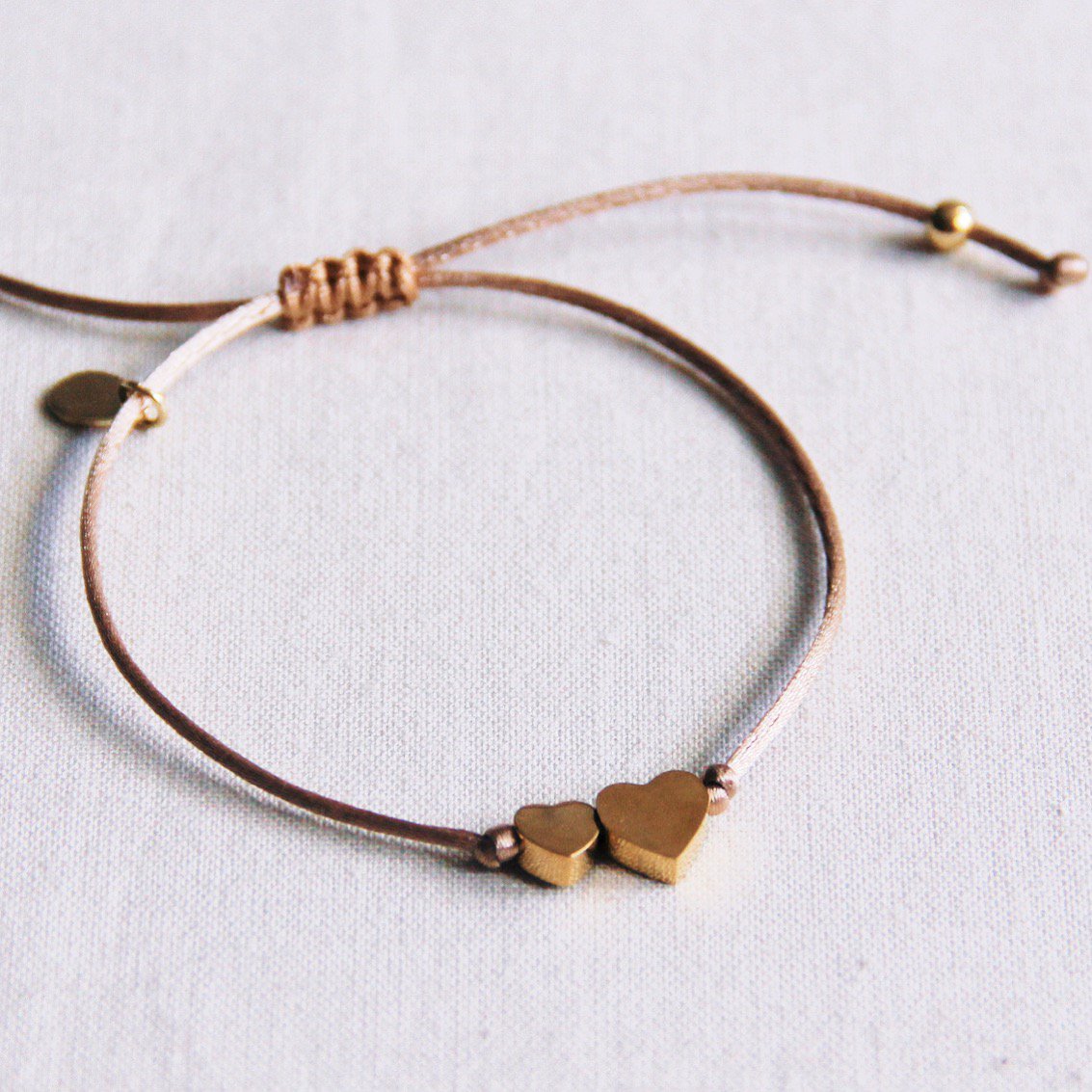Satijnen armband met een klein en groot hart - taupe / goud